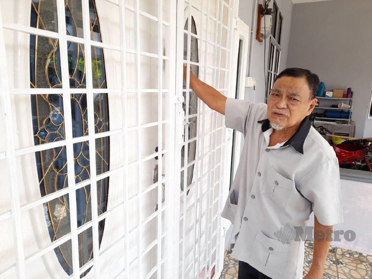 SAID Hassan menunjukkan bagaimana pintu luar bahagian hadapan kediamannya diketuk pada awal pagi di Kampung Paya Rumput, Masjid Tanah dekat Alor Gajah. PHOTO HASSAN OMAR